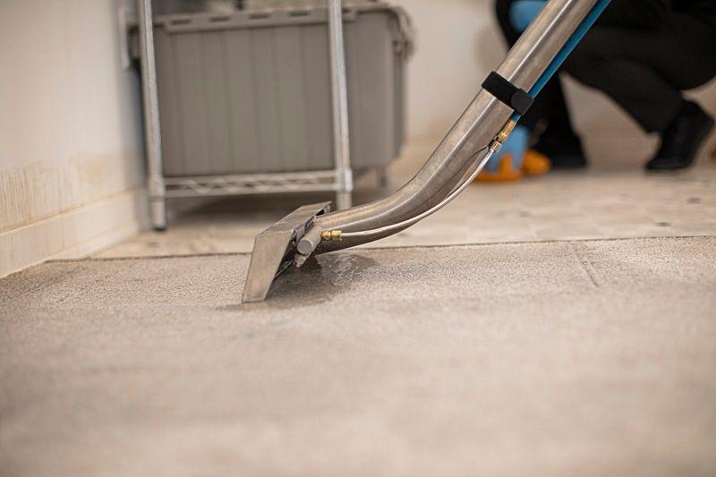 ServiceMaster Restoration By Simons technician is extracting flood waters from a basement floor in Deerfield Illinois