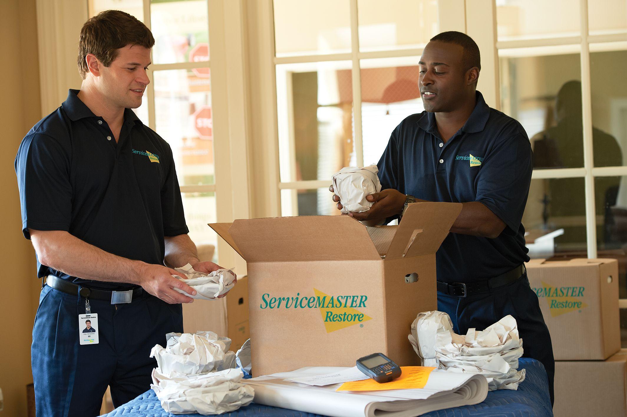 Two ServiceMaster Restoration By Simons techinicians are packing out a home after a fire damage.