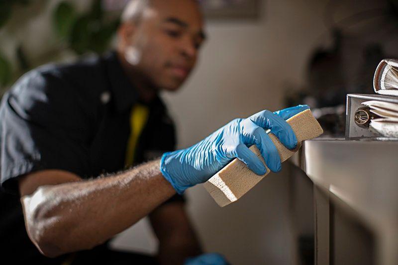 A ServiceMaster Restoration By Simons technician using a soot sponge to safely remove smoke residue from surfaces after a small fire